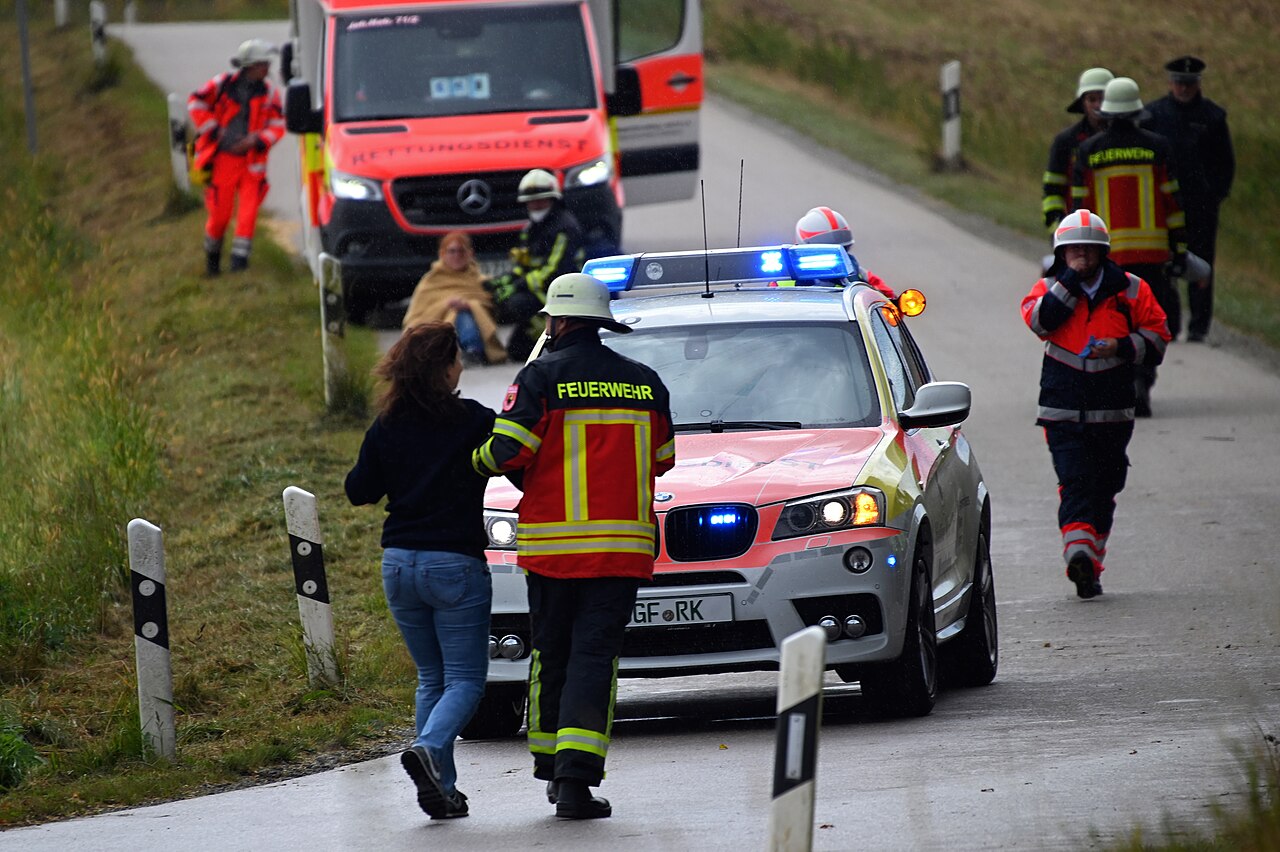 Feuerwehr und Rettungsdienst mit Einsatzfahrzeugen und Übungsbeteiligten auf einer Straße bei der Großübung in Mengkofen